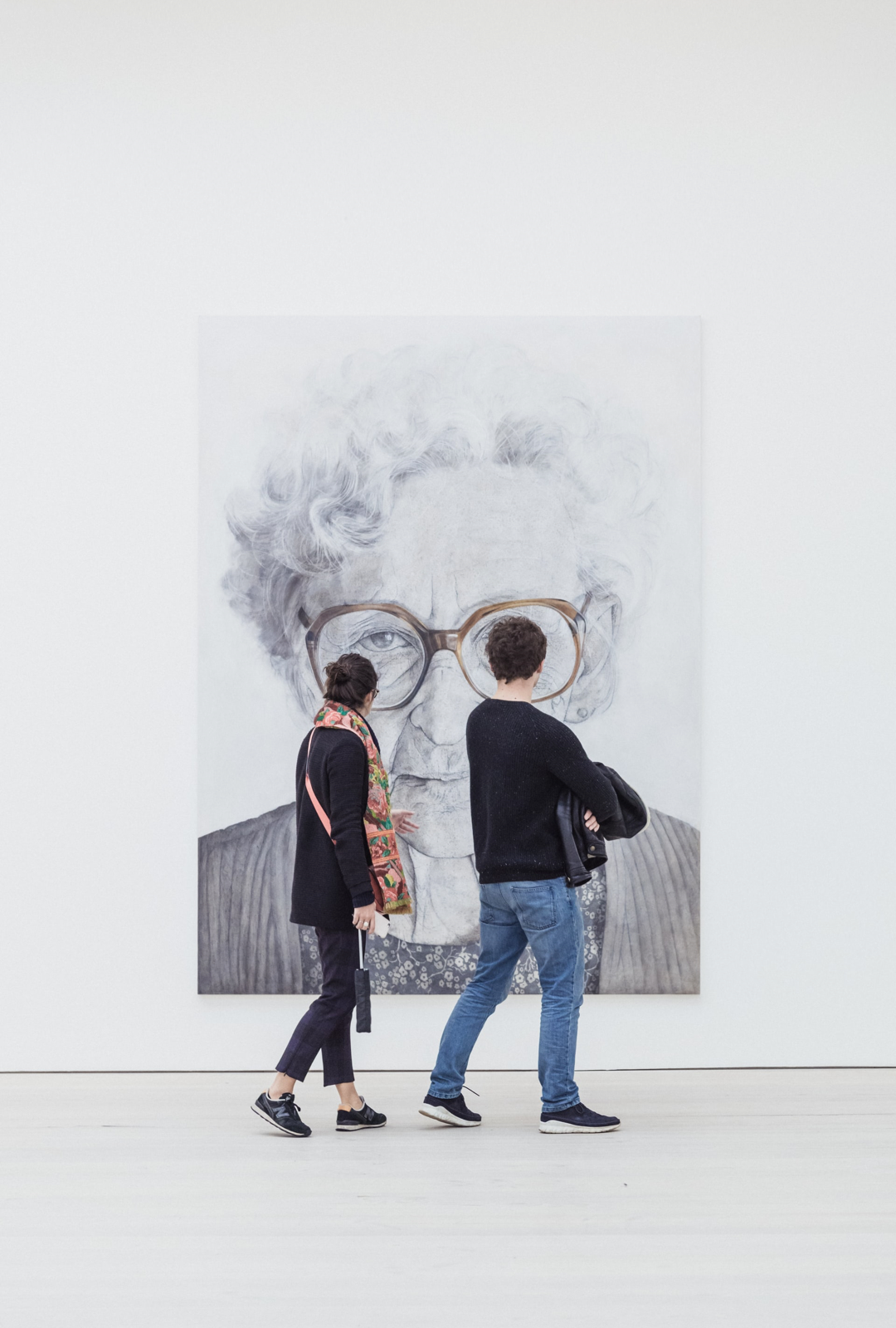 Two people standing in front of a portrait